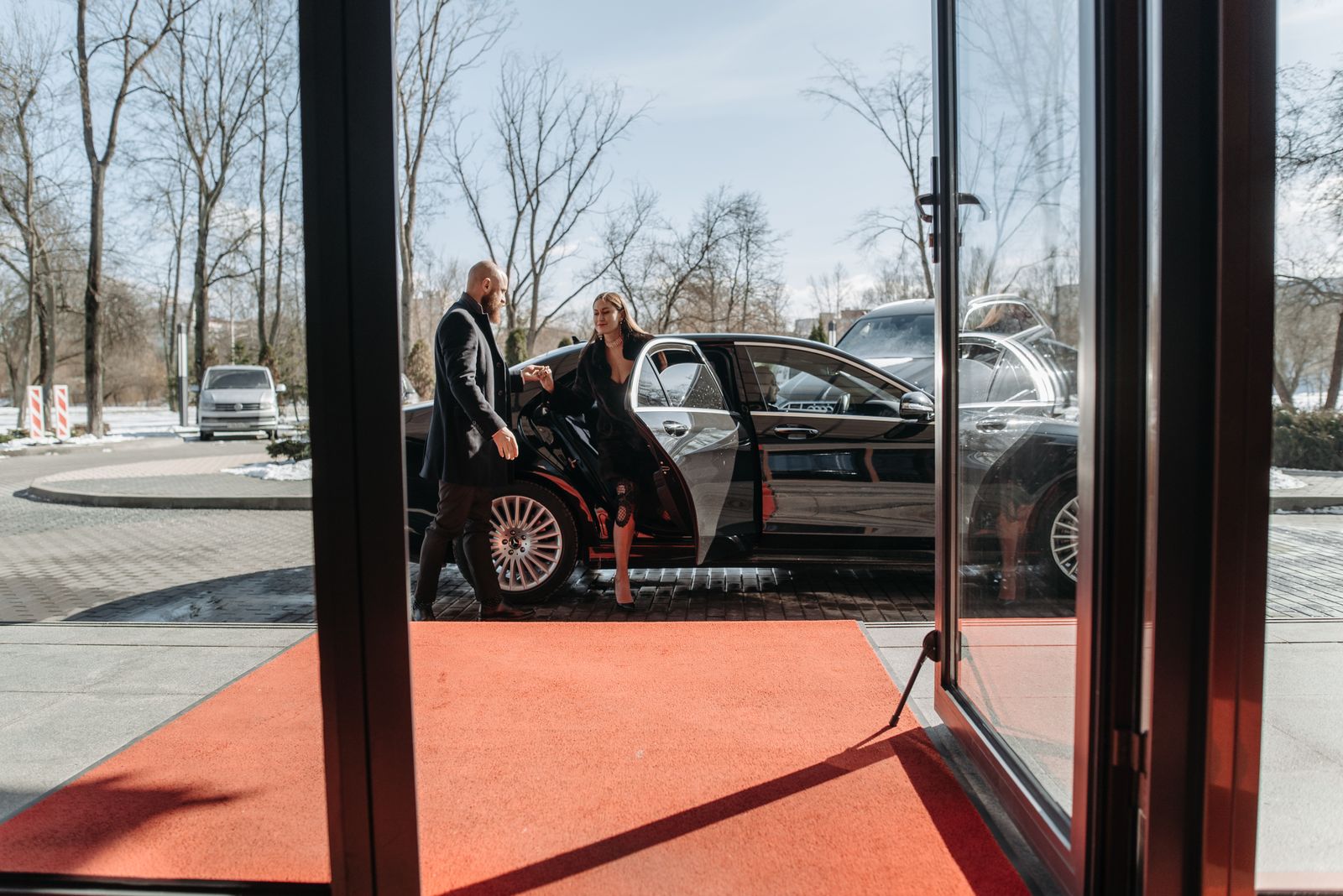 Avante chauffeur helping a guest out of a black luxury car at a venue entrance in Vancouver